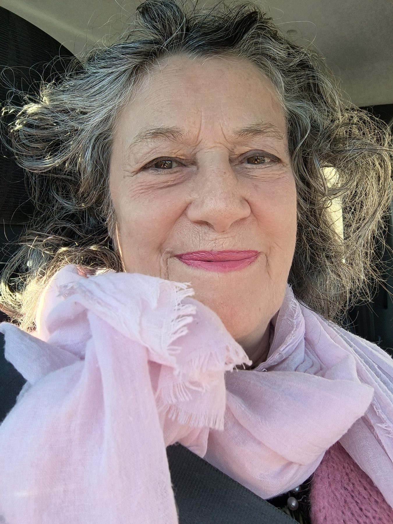 Dominique Levillain en 2025, souriante, une écharpe rose autour du cou